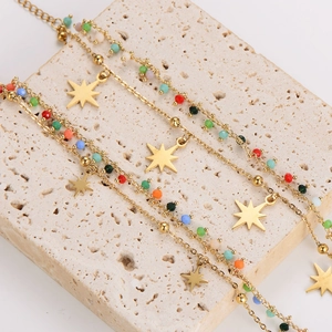 Double-layered gold bracelet with colorful beads and star pendants on travertine stone