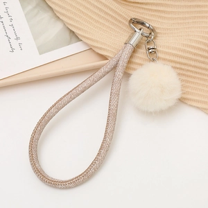 Détail du porte-clés dragonne tissée avec pompon en peluche beige et fermoir métal