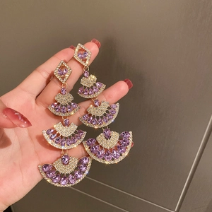 Detail of fan-shaped vintage gold earrings with purple crystals and drop-shaped gems