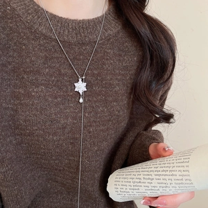 Silver Y-shaped snowflake necklace with a pearl pendant on elegant model in brown sweater