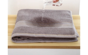 Macro shot of grey-purple cotton towel texture showing high water absorption on wood