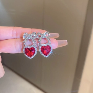 Macro shot of silver bow earrings with large red heart stones and sparkling crystal inlay