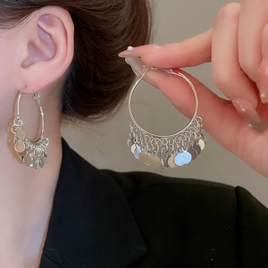 Macro detail of silver layered sequin tassel hoop earrings with metallic fringe finish