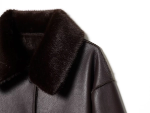 Detail of dark brown leather jacket featuring a premium faux fur collar and shoulder texture