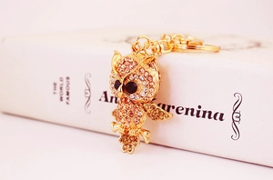 Macro shot of gold owl keychain with pink rhinestones and a polished lobster clasp detail