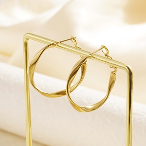 Minimalist gold-plated twisted C-shape hoop earrings for women on a jewelry display stand