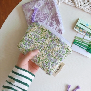 Gros plan sur un petit porte-monnaie en coton à fleurs et pochette brodée violette à zip