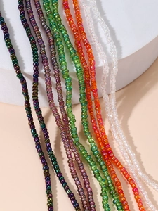 Close-up of bohemian colorful glass seed beads in purple green and orange on display