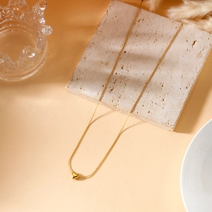 Macro detail of 18K gold-plated heart pendant on marble stone for a luxury look