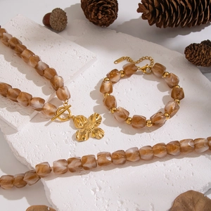 Brown gradient resin beaded jewelry set with gold flower pendant on white stone