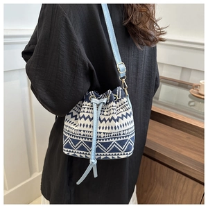 Detail of blue and white geometric canvas bucket bag with light blue drawstring and strap