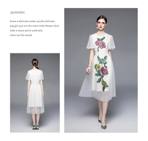 Détail de la broderie florale sur robe en mesh blanc avec motifs roses et jaunes