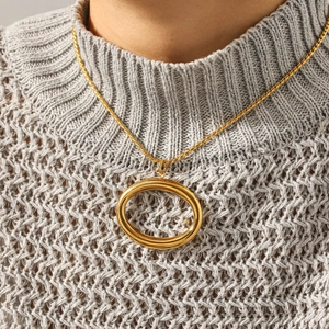 Gold hollow oval pendant necklace with twisted rope chain shown on gray knit sweater