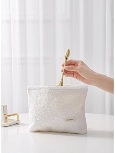 White textured makeup bag with floral relief and a sleek zipper for travel storage