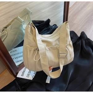 Detail of adjustable strap and pleated drawstring closure on off-white nylon tote bag