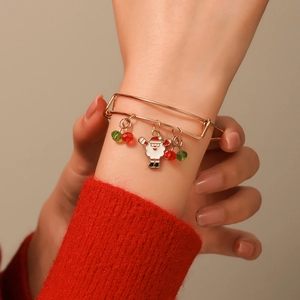 Close-up of adjustable gold Christmas bracelet with Santa Claus charm on model's wrist