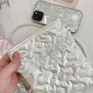 Dettaglio borsa in raso trapuntato bianco con pizzo, fiocco blu e catena di perle