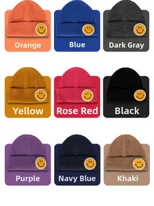 Detail of nine knitted beanies in various colors featuring embroidered smiley face patches