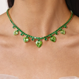 Detail of a gold-tone necklace featuring vibrant green heart-shaped crystal pendants