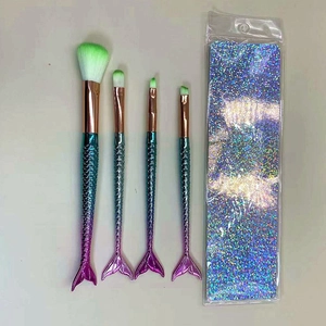 Detail of four mermaid makeup brushes with gradient handles and green fiber bristles