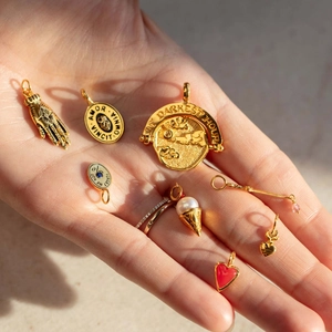 Collection of gold cubic zirconia pendants and rings with engravings held in palm