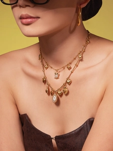 Macro shot of layered gold owl and heart pendants with rhinestone inlay on necklace