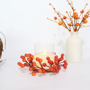 Close-up of orange berry candle ring with a glass holder and lit pillar candle