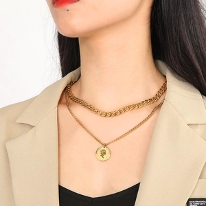 Close-up of double layer gold necklace featuring a chunky chain and vintage coin pendant