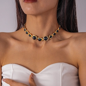 Close-up of vintage choker featuring gold metal frames with oval black resin inlay