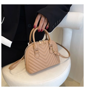 Detail of apricot quilted shell bag with V-shaped stitching and golden zippers