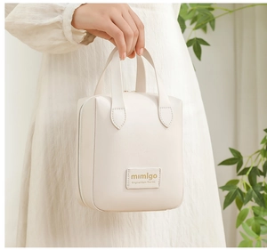 Close-up of a cream white PU leather shell makeup bag with handles and logo detail