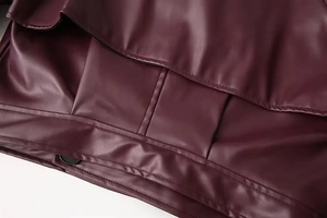 Detailed macro view of burgundy faux leather jacket hem with double stitching and glossy finish