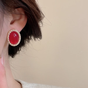 Close-up of vintage red oval stud earring with white faux pearl border on model ear