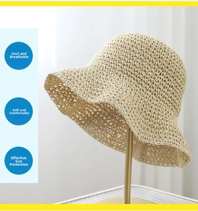 Detail of beige hand-crocheted straw hat with wavy brim on a golden stand for summer