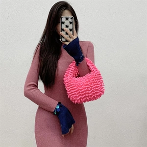 Detail of bright pink plush popcorn texture handbag held by model in mirror selfie