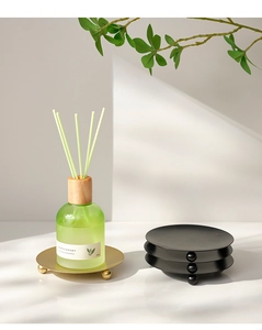 Close-up of golden metal aromatherapy tray with three ball feet on minimalist background