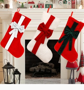 Plush Christmas stockings with bows hanging on fireplace for holiday decoration