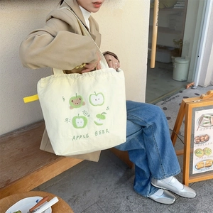 Detailed embroidery of four apple patterns on a cream canvas tote bag with Apple Beer text