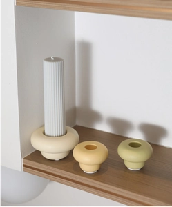 Detail of minimalist ceramic candle holders in cream tones on a wooden shelf display