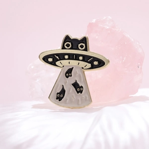 Macro shot of an enamel black cat UFO brooch with fine gold plating and creative detail