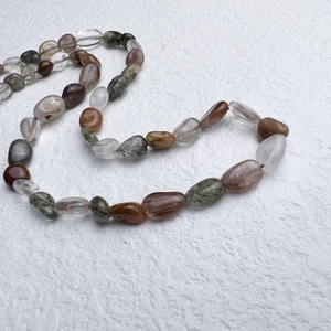 Detailed close-up of irregular natural phantom crystal beads on a stainless steel necklace