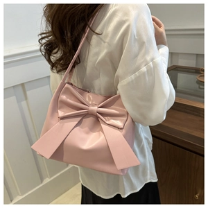 Detailed back view of pink tote bag with oversized bow on a model in a cozy room