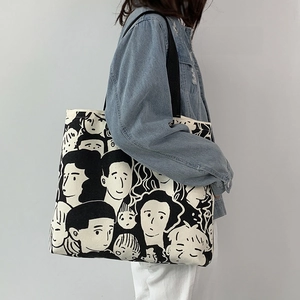 Detail of a large off-white canvas tote bag featuring black artistic sketches on the fabric