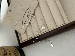 Macro shot of silver snake chain necklace with brushed heart pendant in jewelry box
