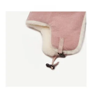 Detail of pink knitted winter hat with white faux fur lining and black plastic buckle