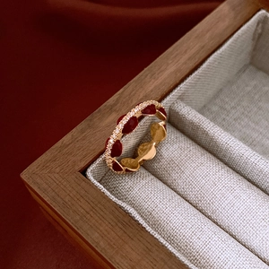 Close-up of golden hollow petal ring with deep red enamel and micro-set zircons