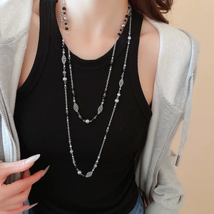 Detail of layered pearl necklace with silver flower charms worn on a casual outfit