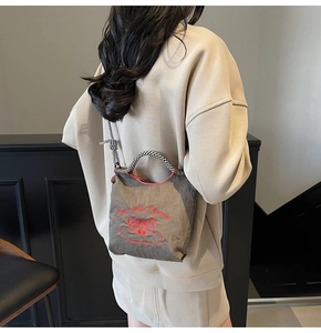 Detail of grey nylon handbag featuring red cherry and bow embroidery and striped handles