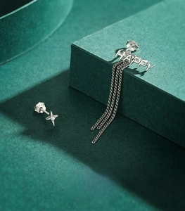 Detail of S925 sterling silver HAPPY tassel earring with star stud on green display