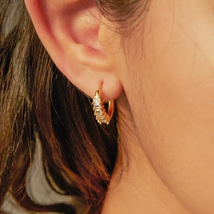 Gros plan de boucles d'oreilles créoles dorées en acier inoxydable serties de zircons